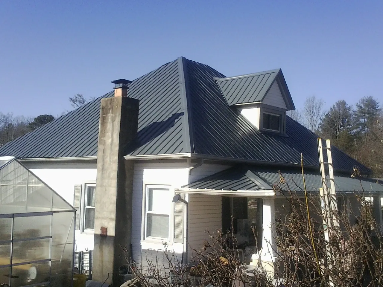 Dark blue standing seam metal roof on a white farmhouse with dormer — Slate & Tile Roof Repair by Roofing Brothers in Rosalia