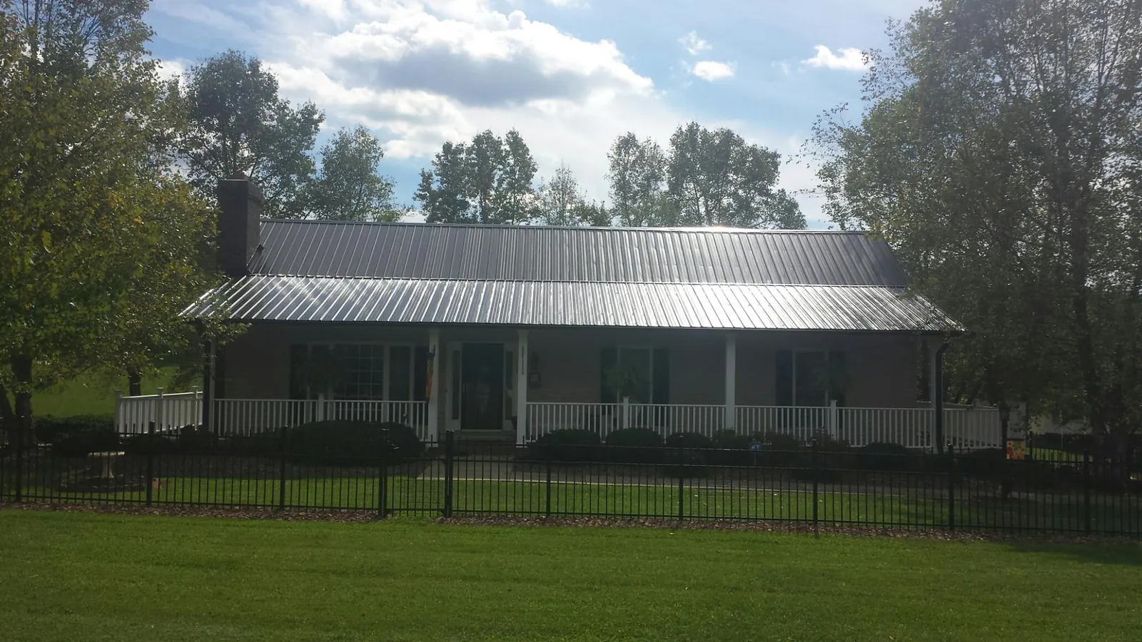 Gray metal roof on a brick ranch with a full width front porch — Gutter Guard Installation work by our crew in Rosalia